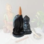 Porte encens pour cônes à reflux en résine sur un fond zen. Cet article est une représentation détaillée du Bouddha en méditation. Son utilisation avec des cônes à reflux donne un effet visuel exceptionnel.