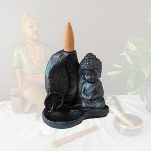 Porte encens pour cônes à reflux en résine sur un fond zen. Cet article est une représentation détaillée du Bouddha en méditation. Son utilisation avec des cônes à reflux donne un effet visuel exceptionnel.