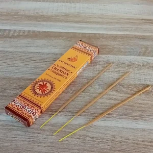 Image de l'encens Ayurvedic Chandan en bâtonnets. Cette boite d'encens est posée sur un fond zen. Il y a 3 bâtonnets d'encens posés à côté. Cette fragrance est en vente chez Zen Aatma - boutique zen et ésotérique.