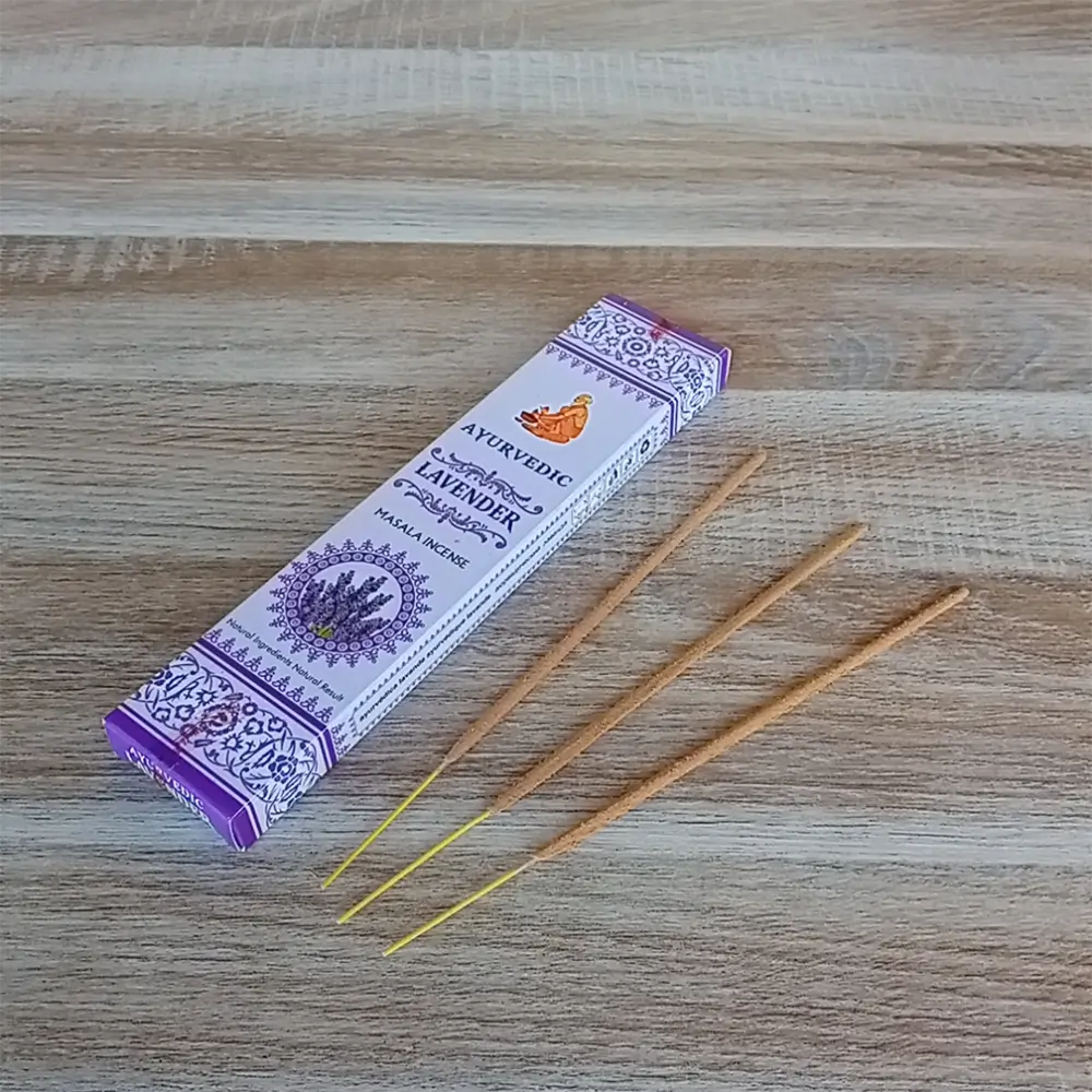 Image de l'encens Ayurvedic Lavande en bâtonnets. Cette boite d'encens est posée sur un fond zen. Il y a 3 bâtonnets d'encens posés à côté. Cette fragrance est en vente chez Zen Aatma - boutique zen et ésotérique.