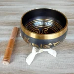 Image d'un bol tibétain sur un trépied Cobra naturel. Objet d'épanouissement personnel idéal pour la méditation, la relaxation et les soins énergétiques le bol chantant tibétain est disponible en 3 tailles : moyen, grand et très grand. Il émet des vibrations sonores harmonieuses grâce à son bâton spécial. Disponible chez Zen Aatma - boutique zen et ésotérique.