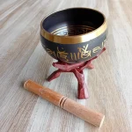 Image d'un bol chantant tibétain sur un trépied Cobra laqué. Objet d'épanouissement personnel idéal pour la méditation, la relaxation et les soins énergétiques le bol chantant tibétain est disponible en 3 tailles : moyen, grand et très grand. Il émet des vibrations sonores harmonieuses grâce à son bâton spécial. Disponible chez Zen Aatma - boutique zen et ésotérique.
