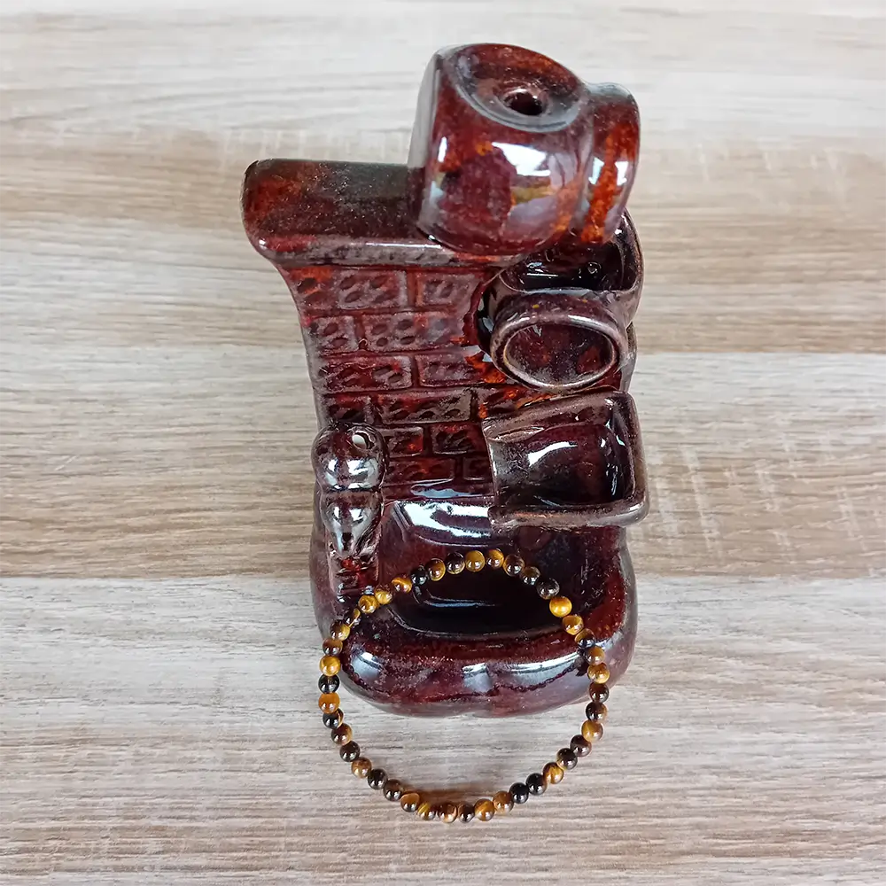 Image du bracelet en pierres d'œil de tigre posé sur un porte encens à reflux pour créer une ambiance zen. Discret, raffiné et énergétiquement puissant, ce bracelet en perles d’œil de tigre de 4 mm est un véritable concentré de protection et d’ancrage. Ce bracelet élastique est en vente chez Zen Aatma - boutique zen et ésotérique.