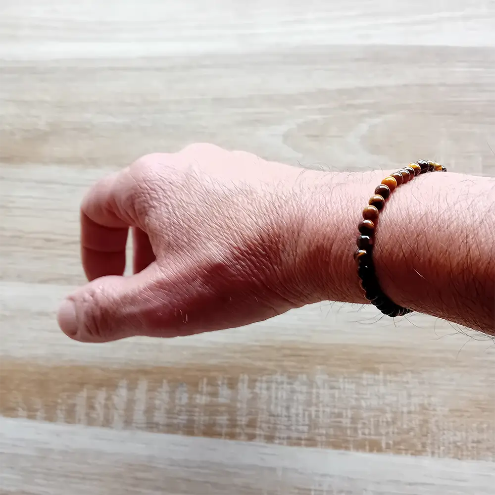Image du bracelet en pierres d'œil de tigre porté au poignet. Discret, raffiné et énergétiquement puissant, ce bracelet en perles d’œil de tigre de 4 mm est un véritable concentré de protection et d’ancrage. Ce bracelet élastique est en vente chez Zen Aatma - boutique zen et ésotérique.