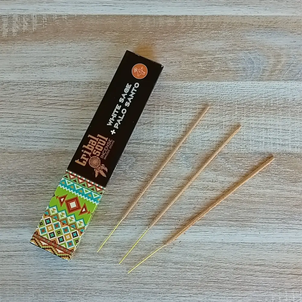 Image de l'encens Tribal Soul Sauge Blanche et Palo Santo en bâtonnets. Cette boite d'encens est posée sur un fond zen. Il y a 3 bâtonnets d'encens posés à côté. Cette fragrance est en vente chez Zen Aatma - boutique zen et ésotérique.